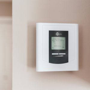 Close-up of a modern digital thermostat mounted on a wall, displaying temperature settings in Celsius.